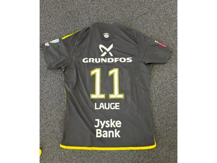 En sort sportstrøje med gule kanter, hvor der på ryggen stod navnet Lauge, nummer 11 samt sponsorerne Grundfos og Jyske Bank, lå fladt ud på et gråt tæppe.