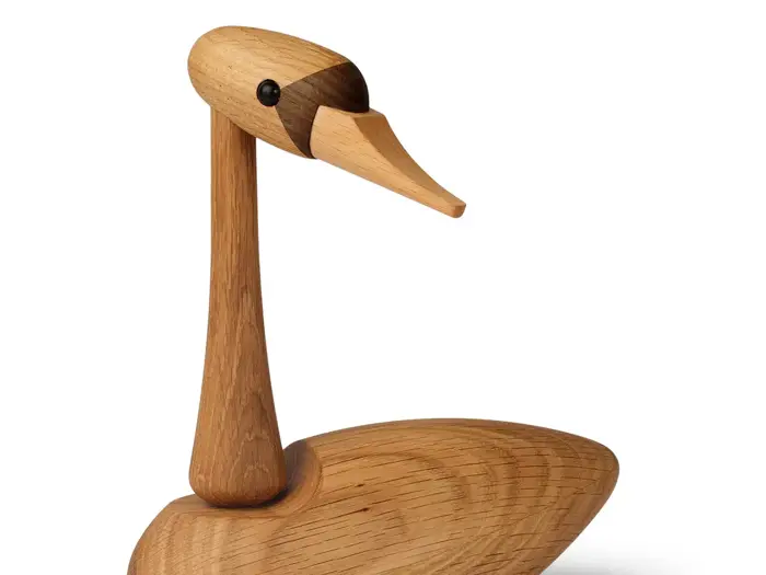 En andeskulptur i træ med en glat, poleret overflade, lang hals og et spidst næb i et enkelt, minimalistisk design.