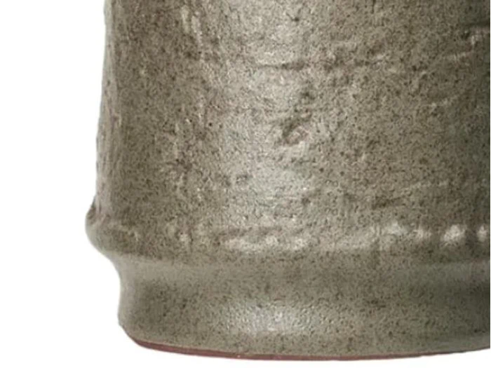 Nærbillede af den strukturerede bund på en grå keramik- eller lerkrukke med en lidt ujævn, mat overflade.