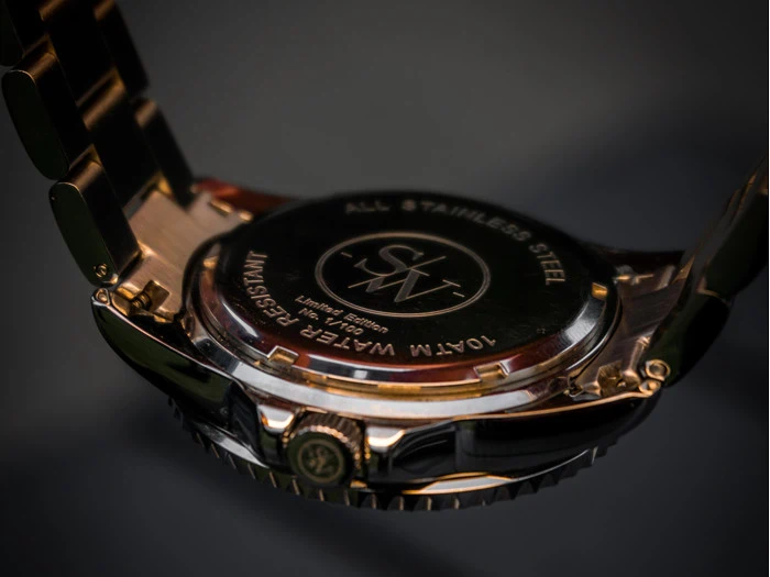 Nærbillede af bagsiden af et armbåndsur med indgraveringer, herunder All Stainless Steel, 10ATM Water Resistant og Limited Edition. Metalarmbåndet er delvist synligt.