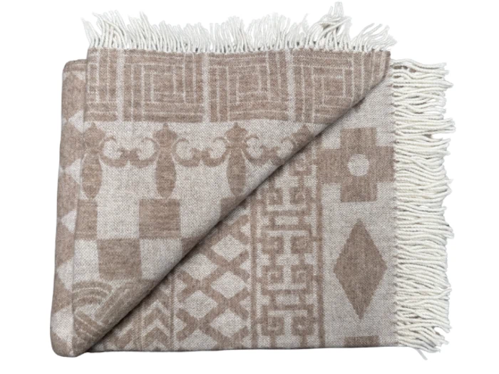 Foldet beige- og hvidmønstret tæppe med frynsede kanter og geometriske og dekorative mønstre.