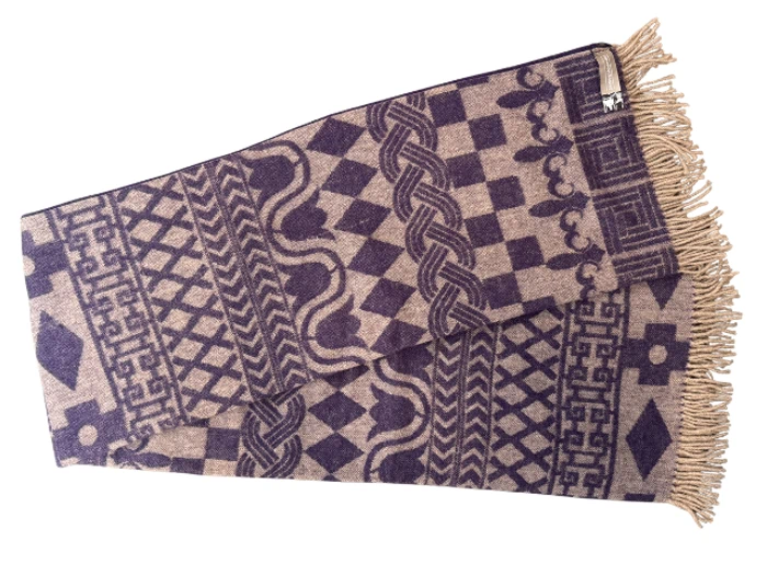 Et foldet tørklæde med geometriske mønstre i beige og mørk lilla og lysebrune frynser i den ene ende.