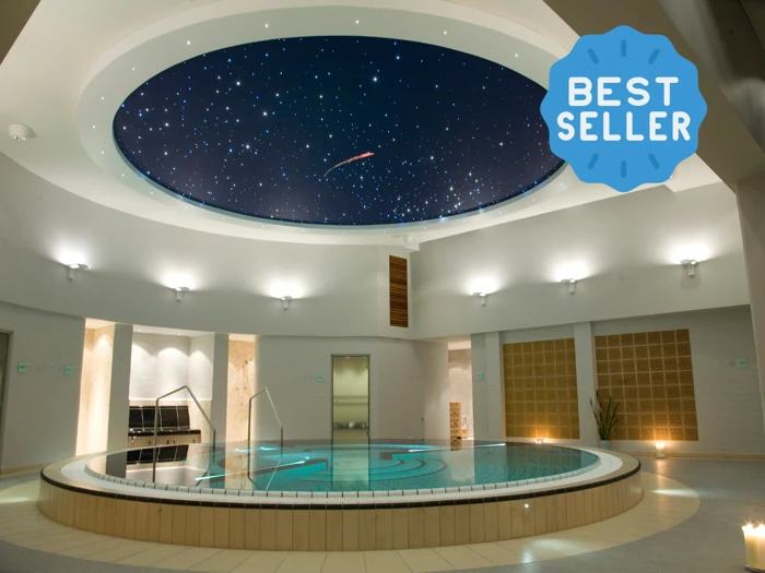 Luksuriøs indendørs spa-pool med cirkulært design, lysende stjernehimmel i loftet og en bestseller-badge i hjørnet.