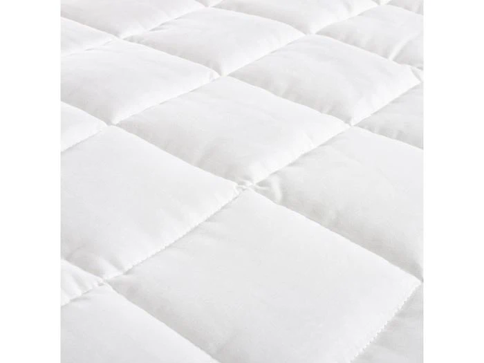 Nærbillede af et hvidt, quiltet stof med jævnt fordelte, polstrede firkanter.