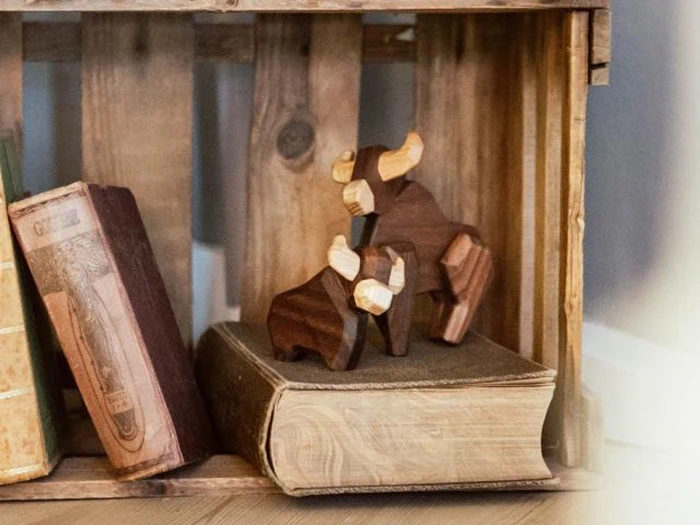 To tyrefigurer af træ er udstillet på en stor bog i en trækasse med gamle bøger i nærheden.