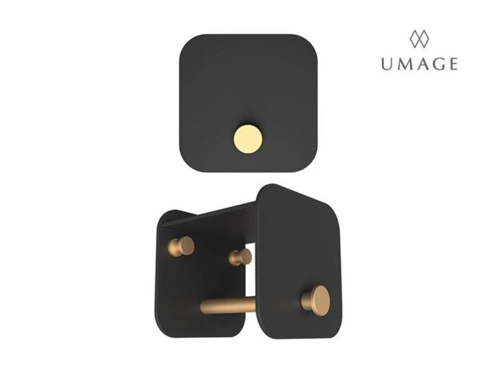 Væghængt toiletpapirholder i sort og guld med et moderne, minimalistisk design, vist oppefra og fra en skrå vinkel. UMAGE-logo i øverste højre hjørne.