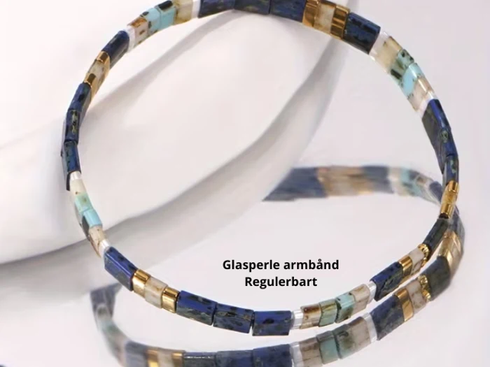 Et perlearmbånd med rektangulære perler i blå, guld, hvid og turkis. Teksten nedenunder lyder Glasperle armbånd Regulerbart.