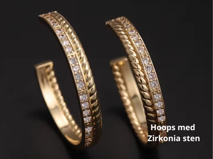 To guldøreringe med indviklede detaljer og indlejrede zirkonia-sten på en sort baggrund. Teksten lyder: Hoops med Zirkonia sten.