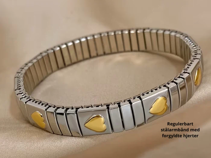 Et sølvfarvet justerbart armbånd i rustfrit stål med guldbelagte hjertecharms på en beige stofbaggrund. Den danske tekst lyder: Regulerbart stålarmbånd med forgyldte hjerter.