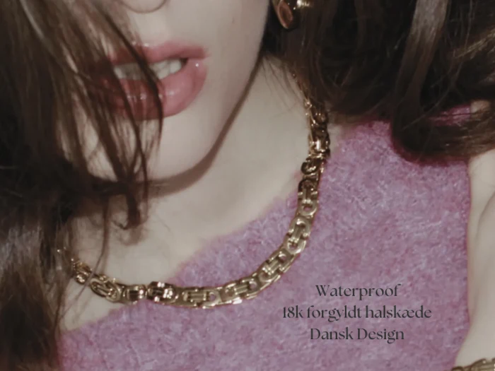 Nærbillede af en kvinde iført guldkæde og pink top. Teksten på billedet lyder: Vandtæt 18k forgyldt halskæde Dansk Design.