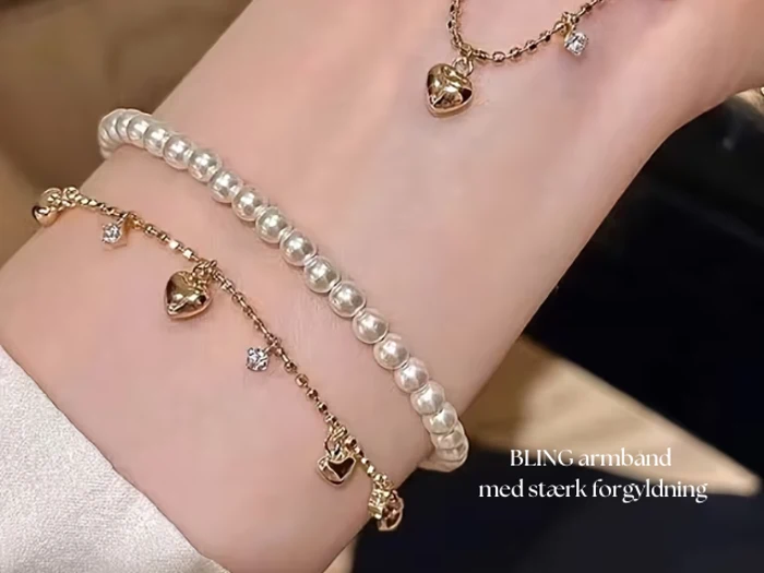 Et håndled bærer to armbånd: et med perler og en guldkæde med små hjerte- og diamantcharms. Den danske tekst lyder BLING armbånd med stærk forgyldning.