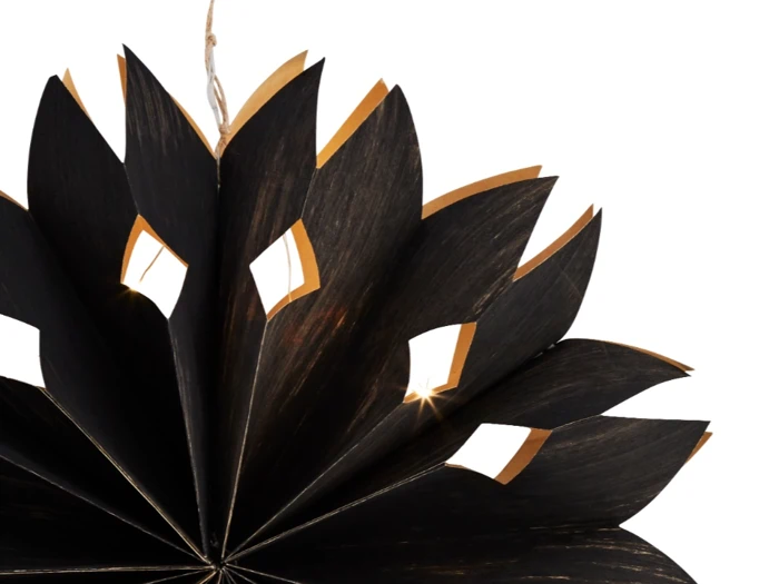 Et nærbillede af en dekorativ sort papirstjerne med udskårne diamantformer og guldkanter, delvist åben mod en hvid baggrund.