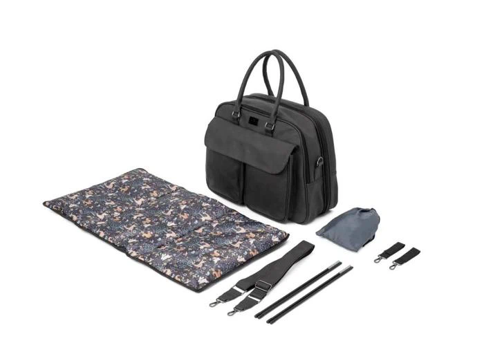 En sort pusletaske med håndtag, et blomstermønstret pusleunderlag, en grå pose, en sort strop og to sorte stropvedhæng på en hvid baggrund.