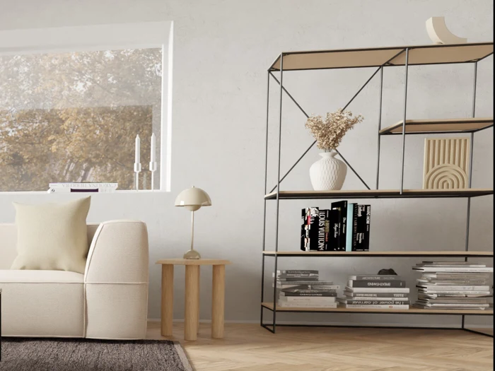 Minimalistisk stue med en beige sofa, et lille sidebord i træ med en lampe og en moderne bogreol med bøger, en hvid vase med tørrede blomster og pyntegenstande.