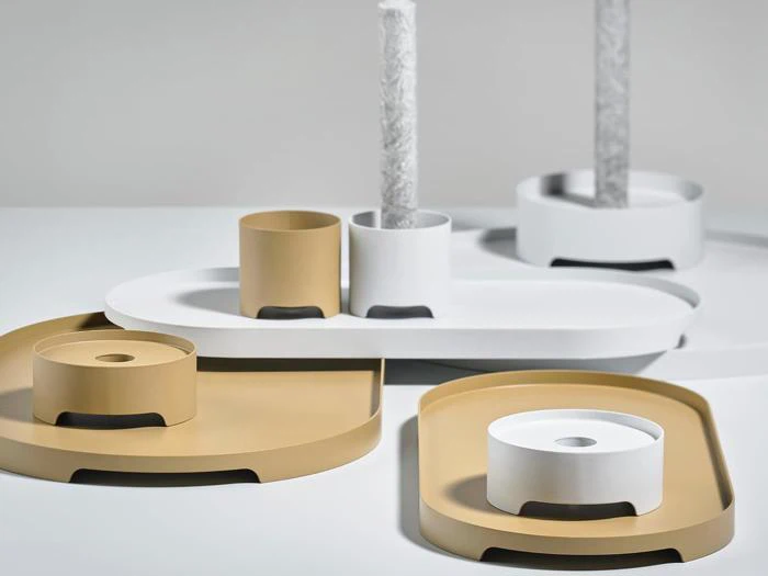 Minimalistiske hvide og solbrune bakker og cylindriske holdere arrangeret på en lys overflade med glatte, geometriske former og moderne design.